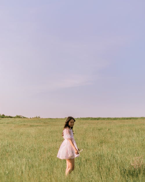 Woman in White Dress Standing on Grass Field