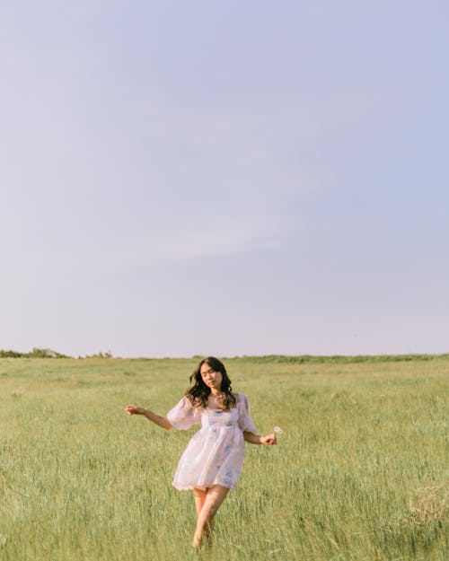 Woman in White Dress Standing on a Grassy Field
