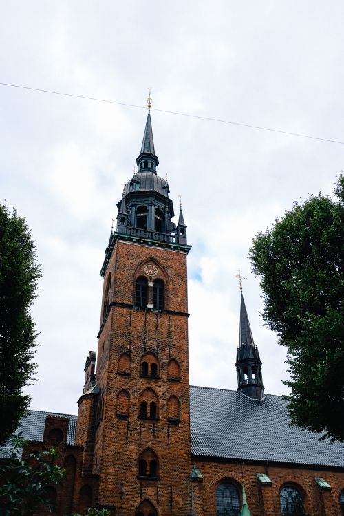 Free Gothic church spire against cloudy sky in Copenhagen, Denmark, showcasing unique architecture. Stock Photo