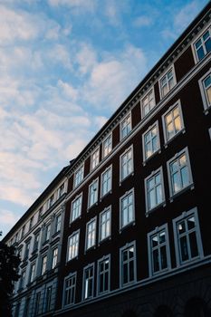 A striking view of a multi-story urban building against a blue, cloudy sky at dusk.