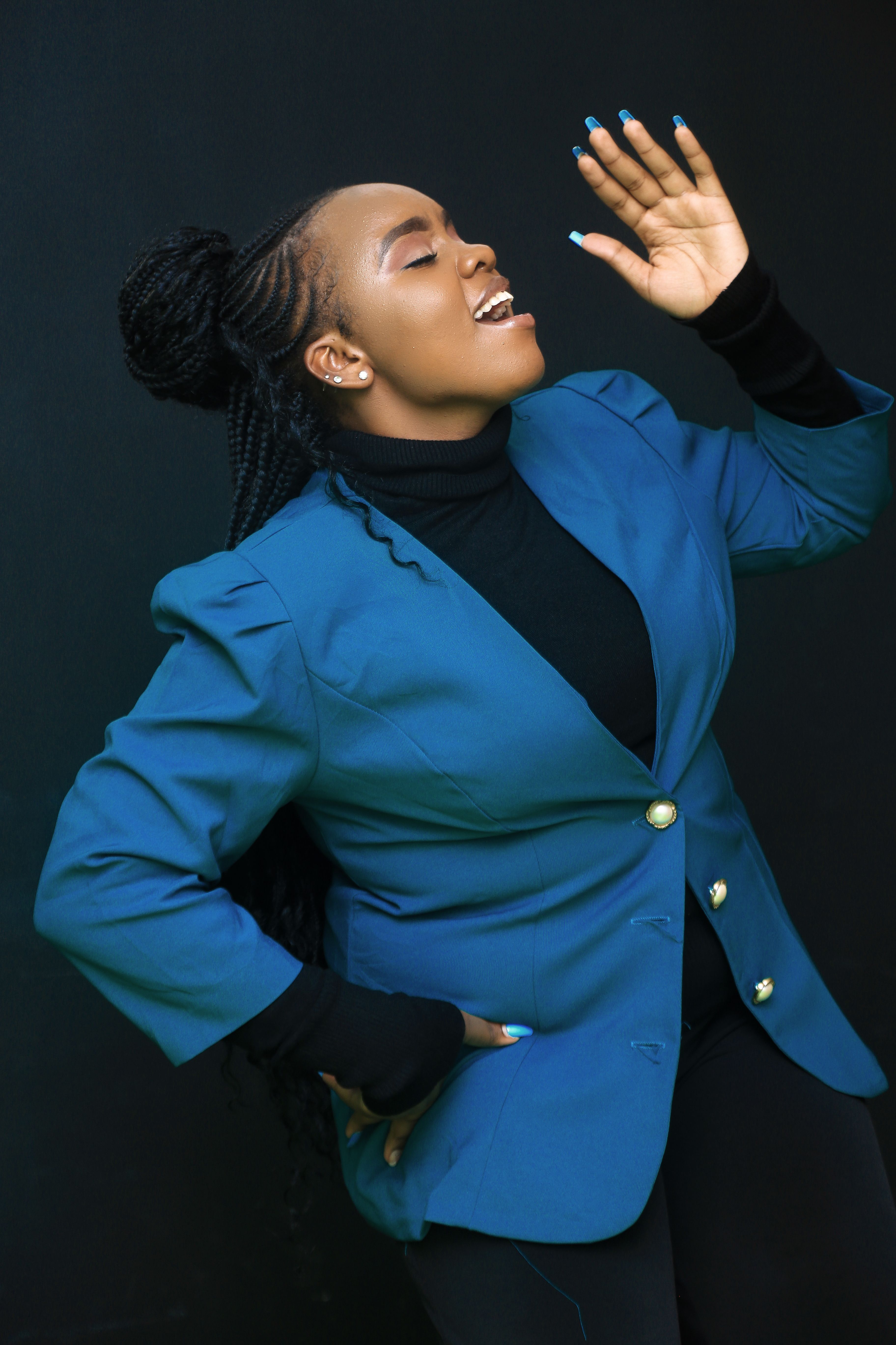 Dynamic studio portrait of a fashionable woman in blue, passionately singing.