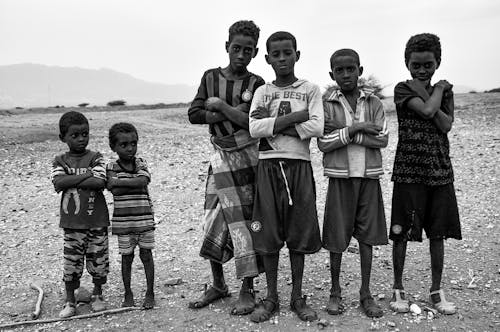 A Grayscale Photo of Young Boys Standing Together with their Arms Crossed