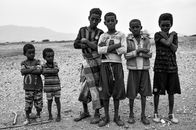 A black and white photo showing Eritrean boys with arms crossed, standing outdoors.