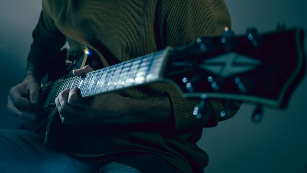 A musician deeply focused while playing an electric guitar indoors.