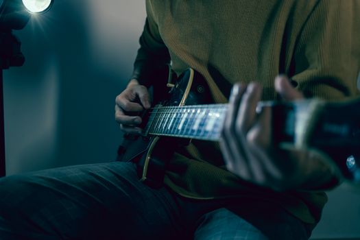Dynamic close-up of a musician skillfully playing an electric guitar with a focused mood.