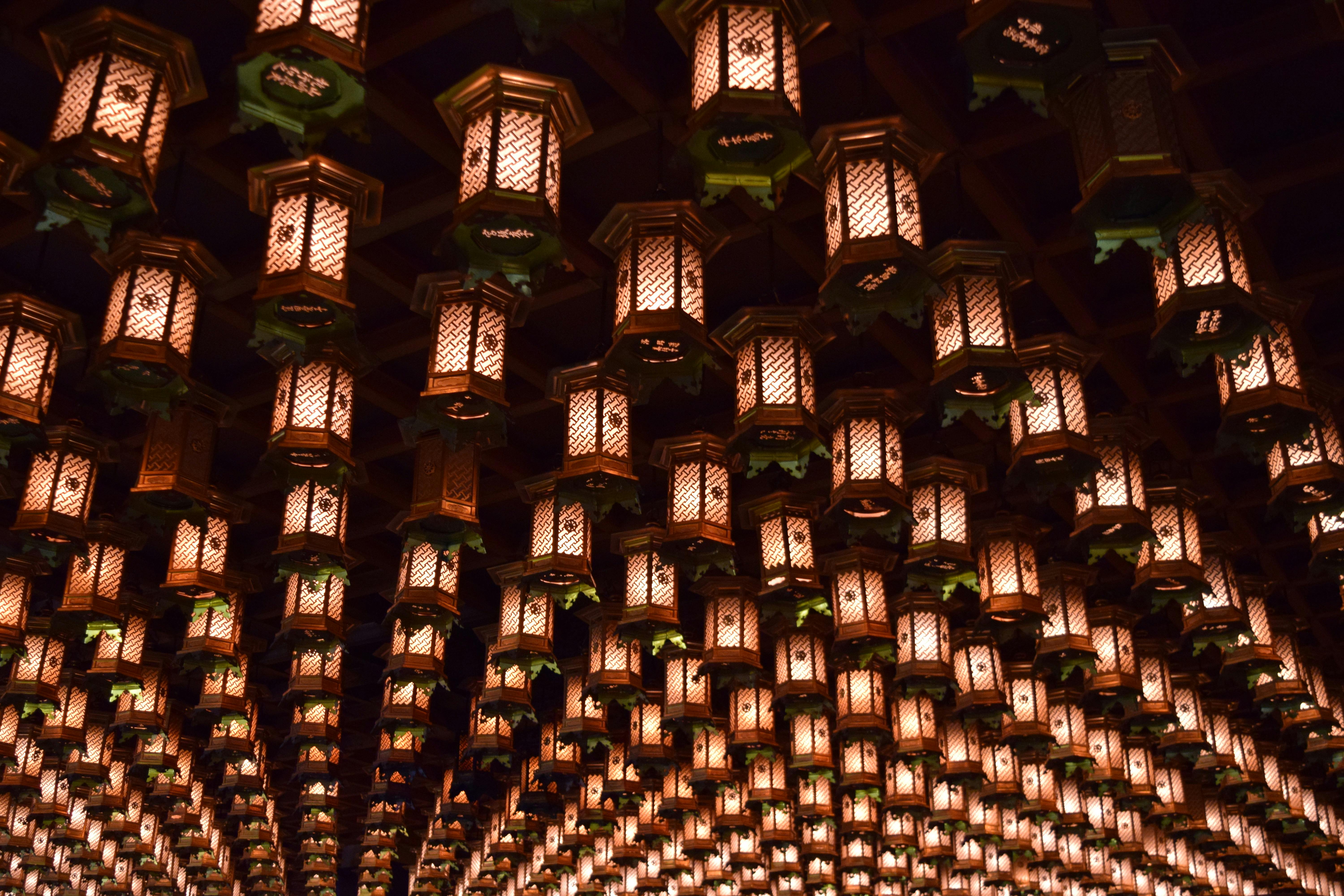 A stunning view of traditional Japanese lanterns illuminating the ceiling of a temple at night.