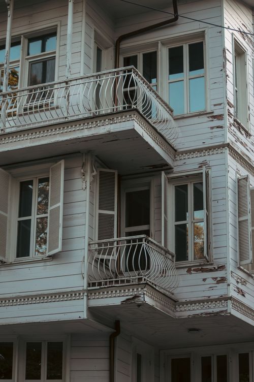 Free A rustic white wooden house with balconies and window shutters in a serene setting. Stock Photo