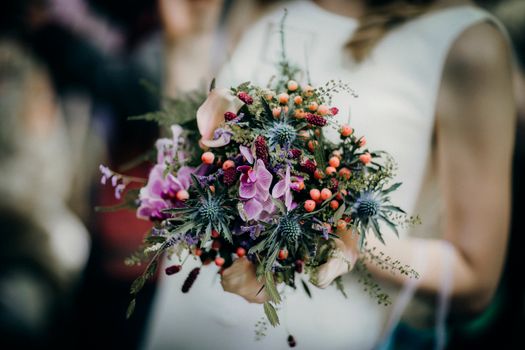 A close-up of a bride holding a vibrant floral bouquet, perfect for weddings.