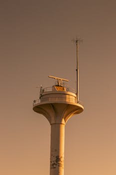 A tall communication tower with multiple antennas, viewed during a warm sunset in Istanbul.