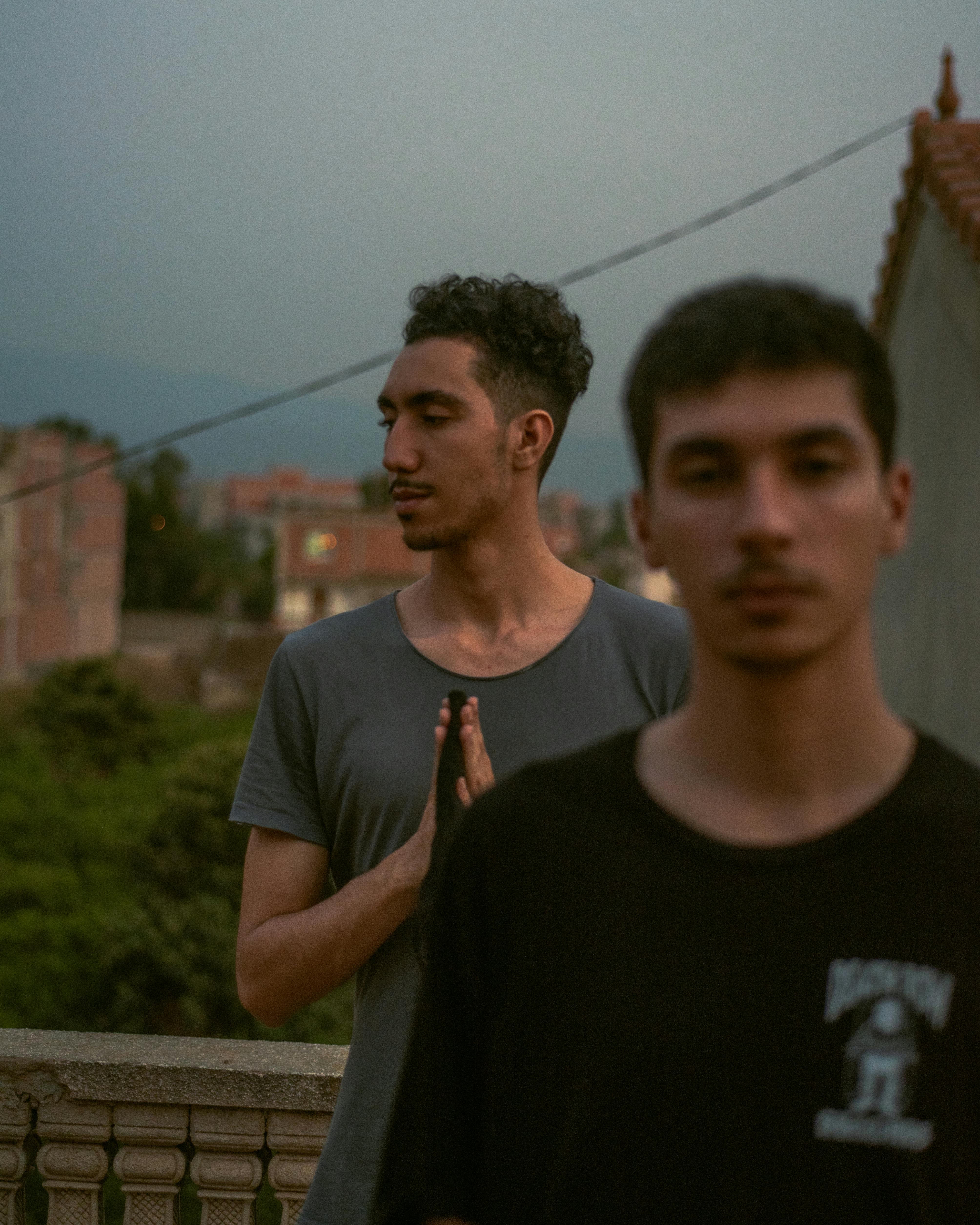 Two young men on a rooftop in Ouled Chebel, Algeria, captured during twilight.