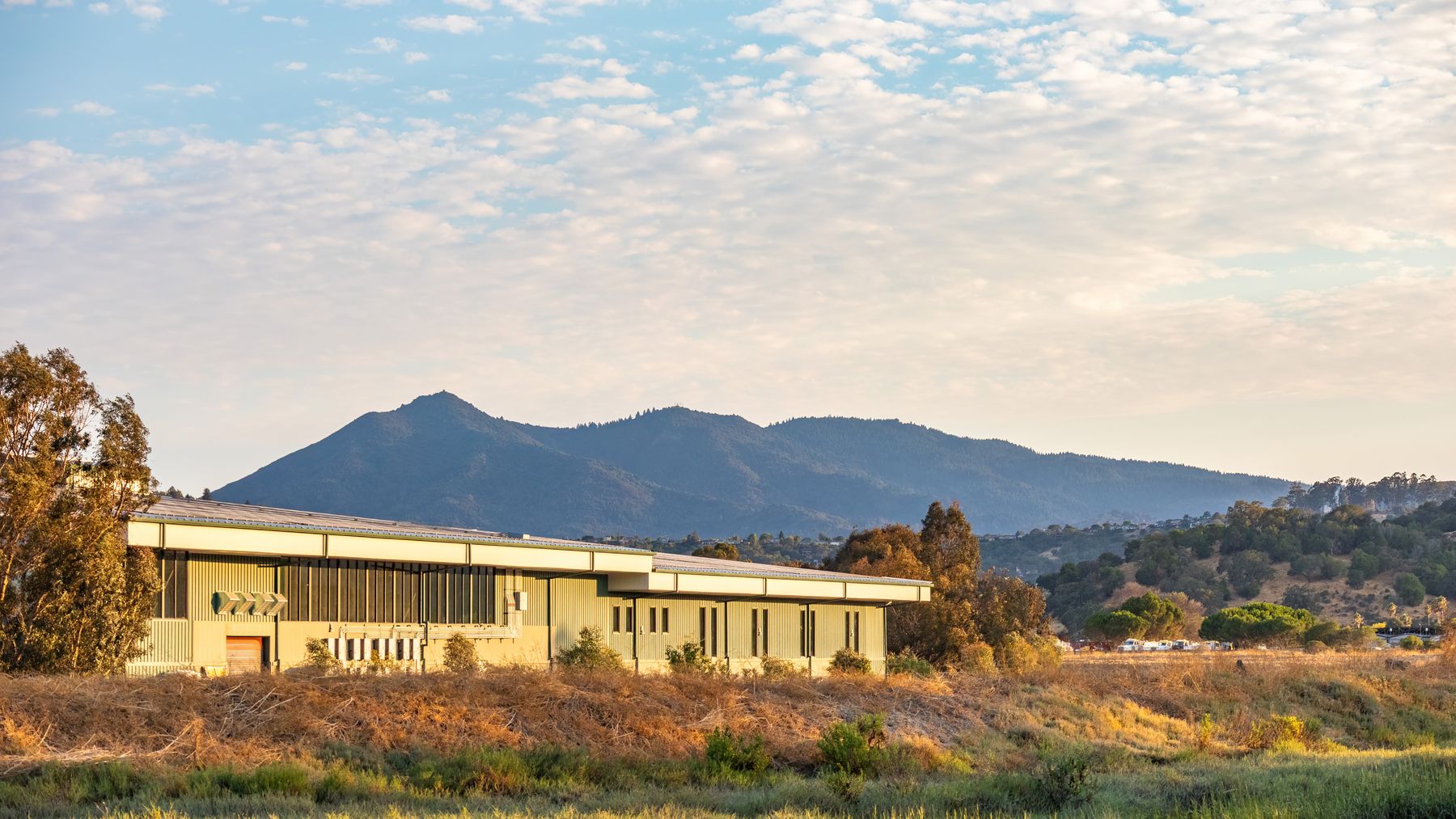 A long low plant building set against a mountain range — photo by Robert So on Pexels