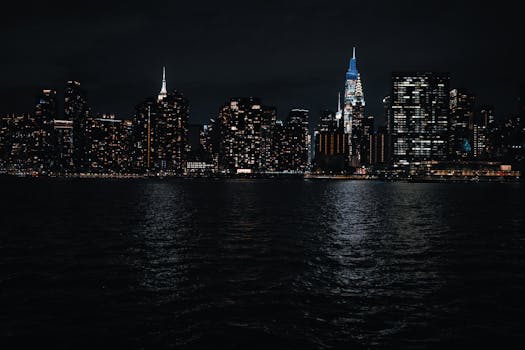 Captivating view of New York City skyline at night with glowing city lights reflecting off the water.