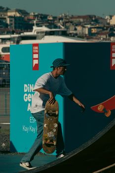 A skateboarder holding his board at an outdoor festival ramp.