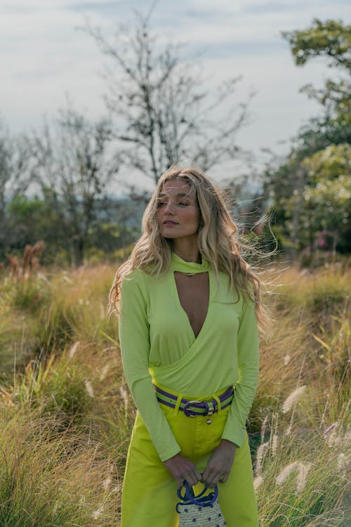 Woman in Green Long Sleeve Top Standing on Green Grass Field