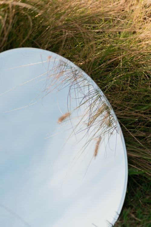 Free A mirror reflecting the sky, surrounded by grass, creating a serene natural landscape. Stock Photo