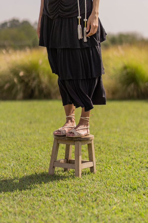 Person in Black Dress Standing on a Wooden Stool