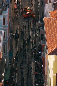 Aerial view of a busy cobblestone street in İstanbul with people and taxis lining the street.