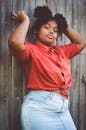 一位年轻女子身穿红色休闲上衣和牛仔裤，在户外自信地摆出时尚姿势