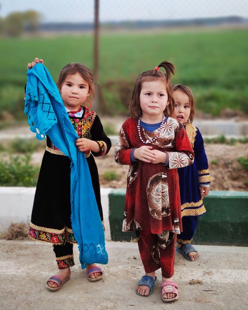 Free Three young girls wearing colorful traditional clothing standing outdoors on a sunny day. Stock Photo