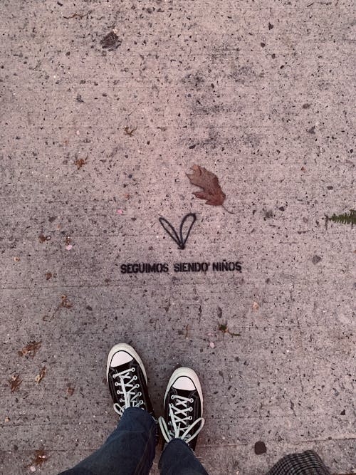 Person Wearing Black and White Sneakers Standing on Gray Concrete Floor