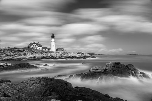 Free Black and white long exposure of Portland Head Light with dramatic sky and rocky shoreline. Stock Photo