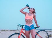 在迪拜沙漠骑行时，女自行车手补充水分，展现了健身与积极的生活方式