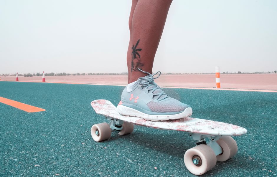 A skateboarder glides on a vibrant road in Dubai, showcasing street style and sport.
