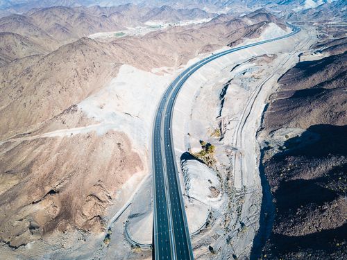 Free Aerial drone view of a road winding through the Al Gharbia desert landscape in Abu Dhabi. Stock Photo