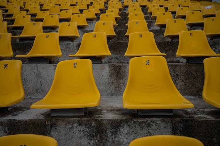 Rows Of  Yellow Plastic Chairs With Umbers