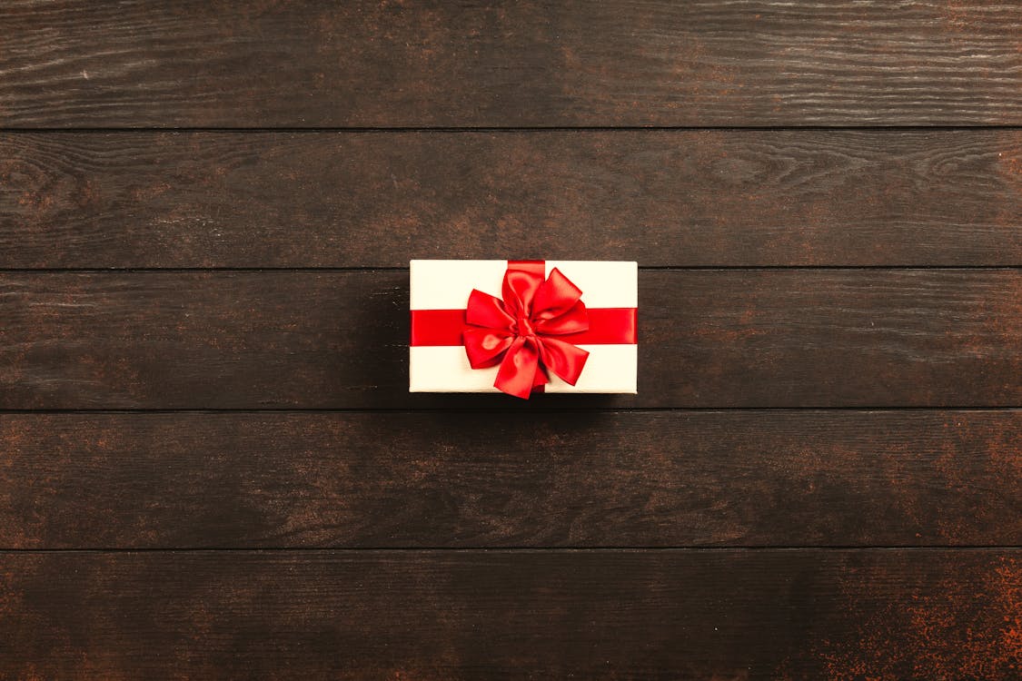 Rectangular White And Red Gift Box on wood floorboards