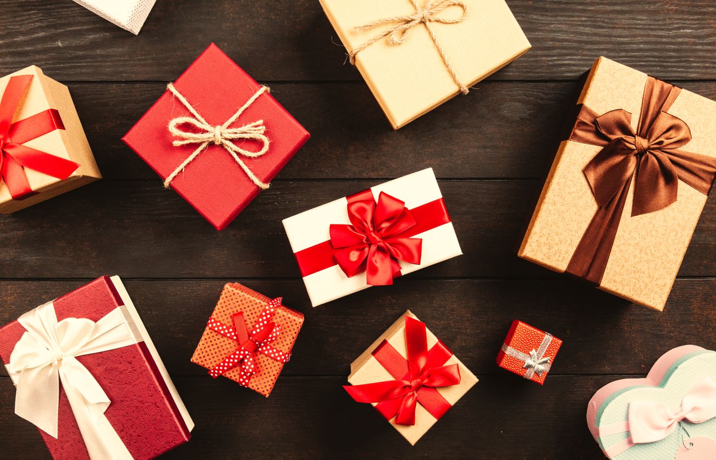 Top view of various wrapped gifts with bows on a wooden table, perfect for Christmas or celebrations.