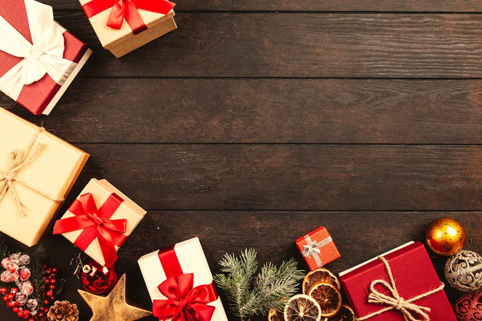 Red and white wrapped Christmas gifts and ornaments on wooden surface.