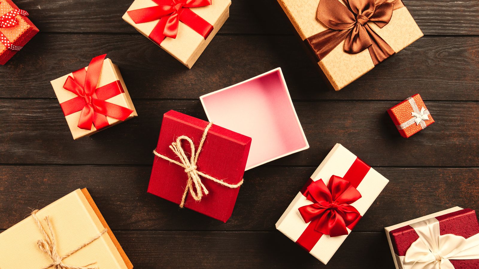 Wrapped gift boxes with red ribbon on a dark wooden surface