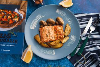 Delicious salmon fillet served with potatoes and mushrooms on a stylish blue plate.