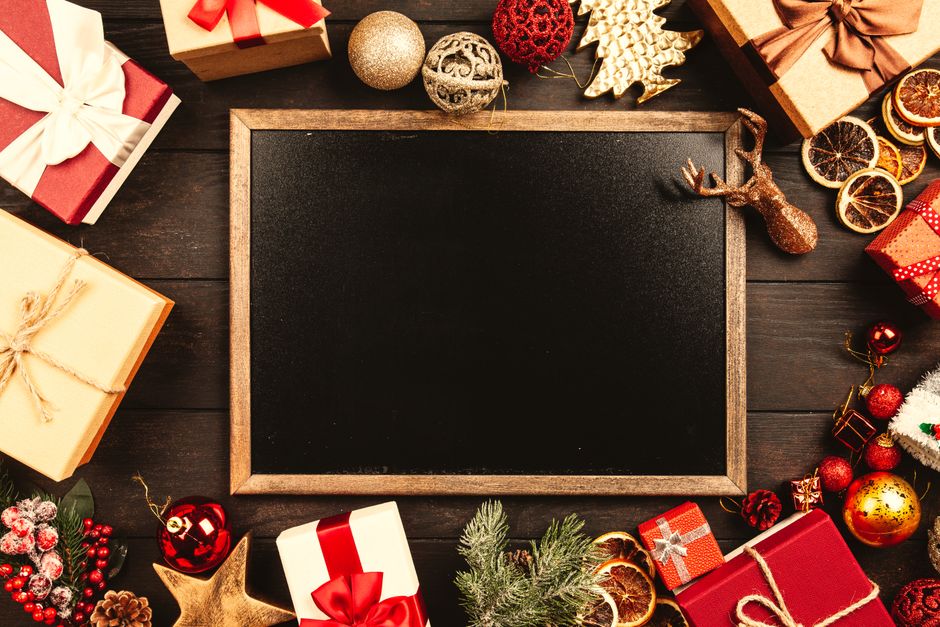 Christmas blackboard surrounded by gifts and ornaments, perfect for holiday greetings.