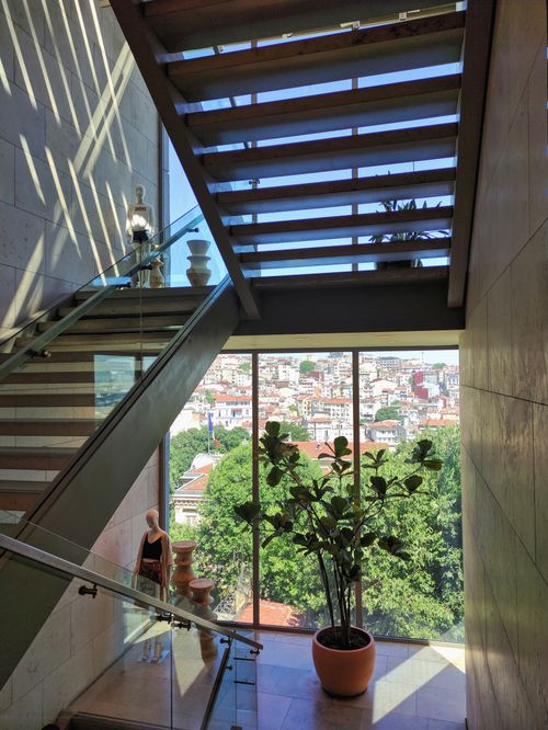 Free A scenic indoor staircase with a city view through large windows, featuring a potted plant. Stock Photo