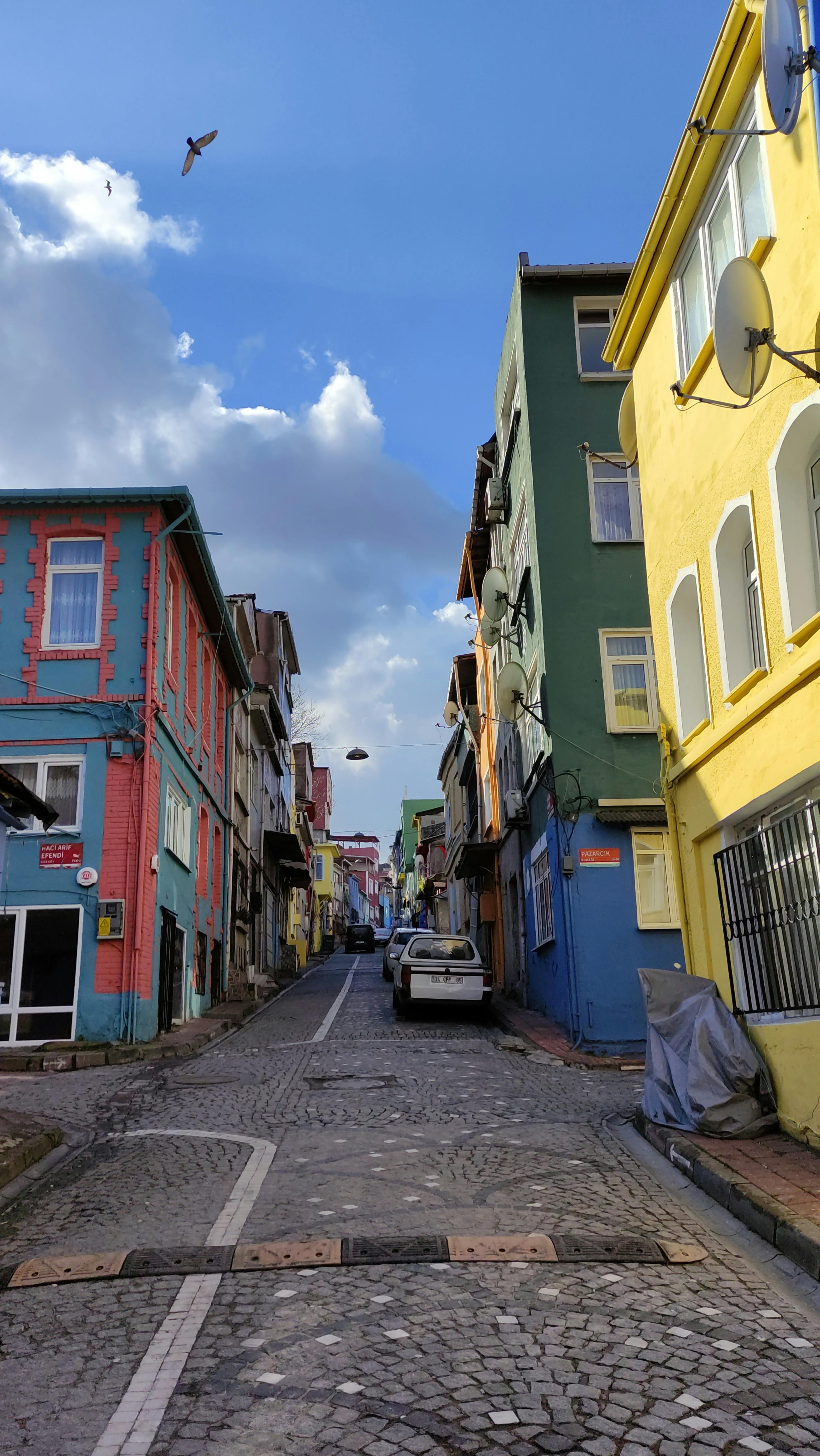 A vibrant alleyway lined with colorful buildings and cobblestone path under a clear sky.