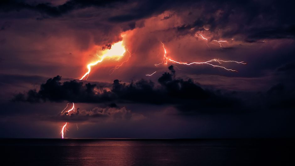 Capturing the striking lightning bolts in a dramatic night sky over the ocean.