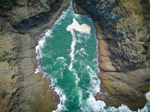 Aerial View of a Turquoise Pond inside Brown Rocks