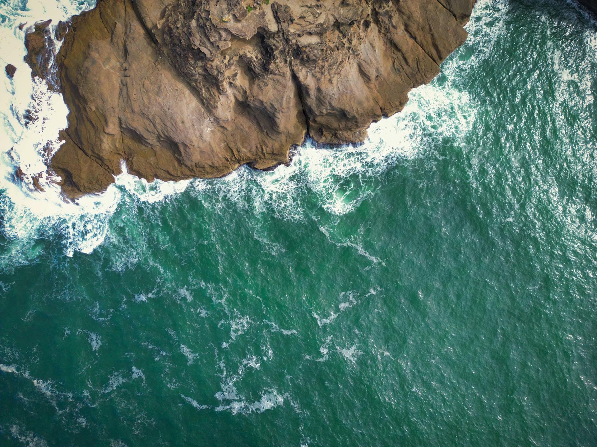 A breathtaking aerial view of the rocky Newcastle coast with crashing ocean waves.