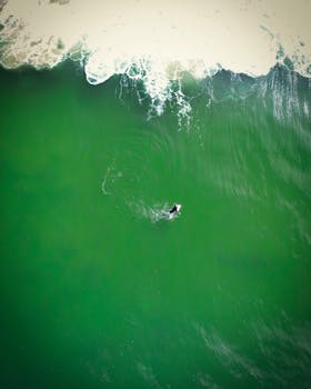 Drone shot of a lone surfer riding green waves in Newcastle, NSW, Australia.