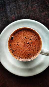 A top view of foamy Turkish coffee in a white ceramic mug and saucer, captured in Turkey.