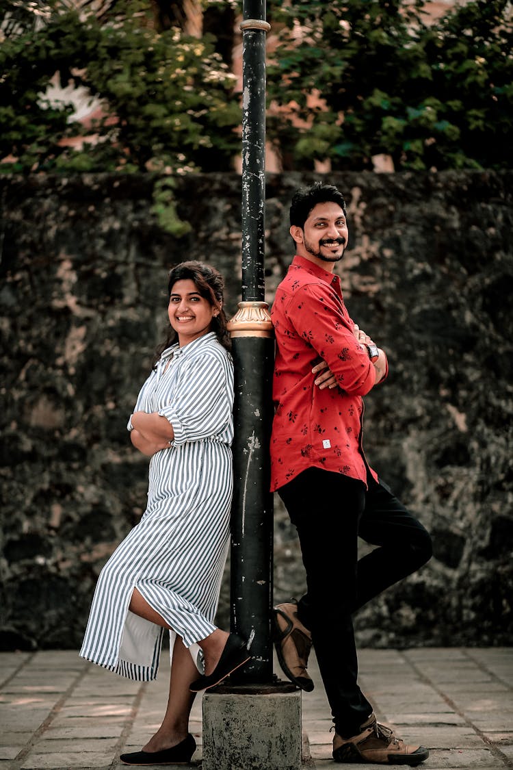 A Man And Woman Leaning On The Pole