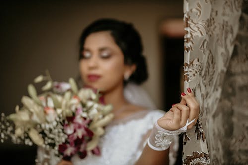 Woman in a Wedding Dress Holding a Curtain