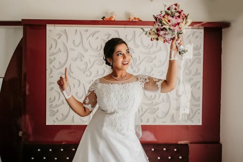 Woman in Bridal Gown Holding Bouquet of Flowers