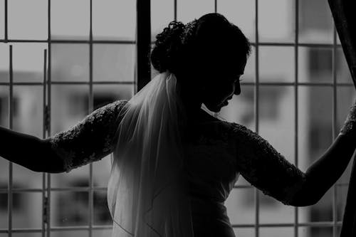 Woman in a Wedding Dress Standing by the Window