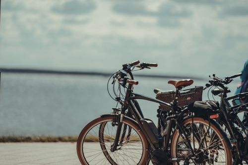 Free Bicycles parked near a tranquil beachside on a cloudy day, perfect for travel themes. Stock Photo