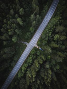 A stunning aerial photograph capturing an intersection within a lush forest from above.