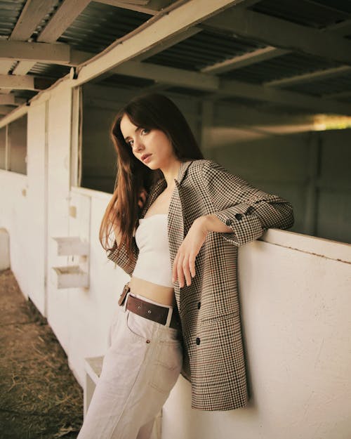 A Portrait of a Woman in a Plaid Blazer Leaning on a Wall