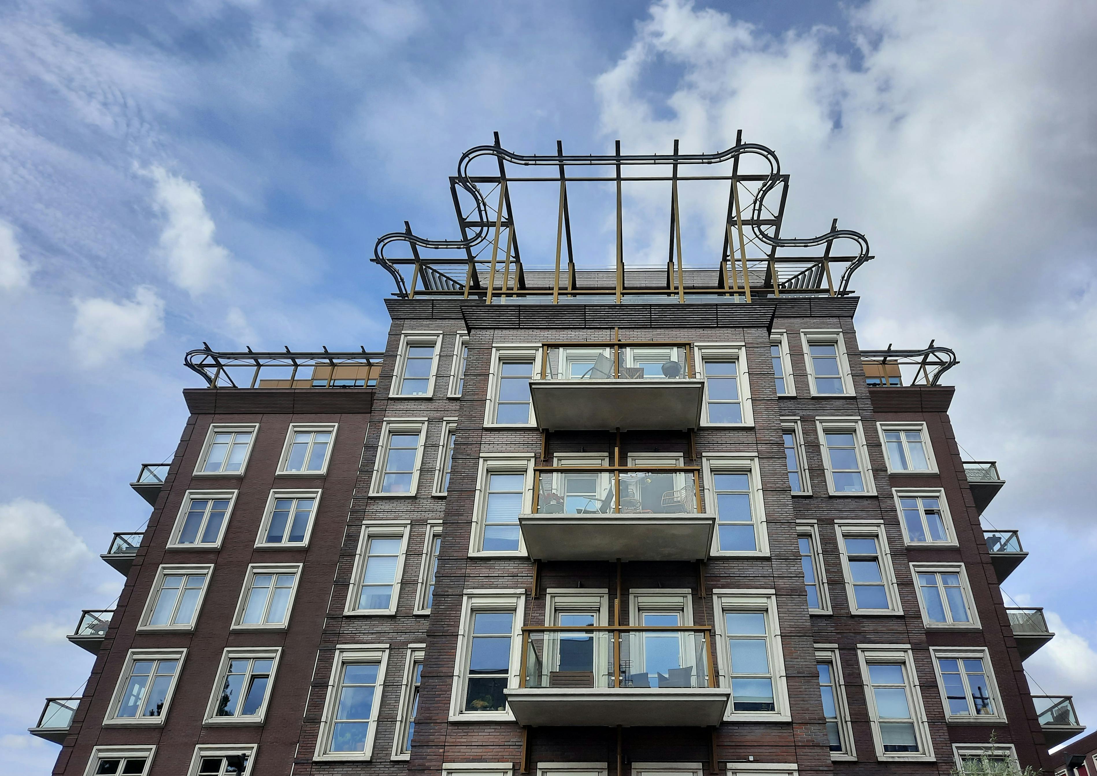 a low angle shot of a building with glass windows under the blue sky and white clouds